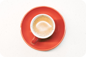 Taza de café vista de arriba con taza y platos naranja.